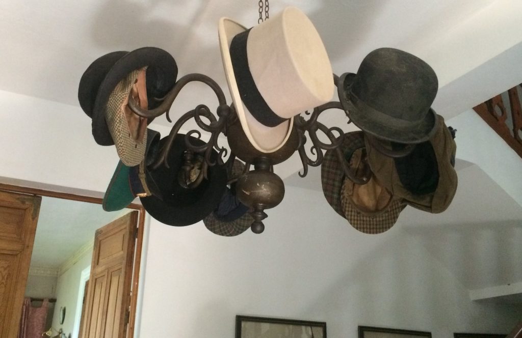 An old chandelier being used as a hat stand, with an array of hats
