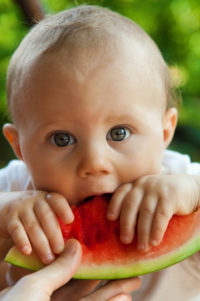 A baby eating a melon