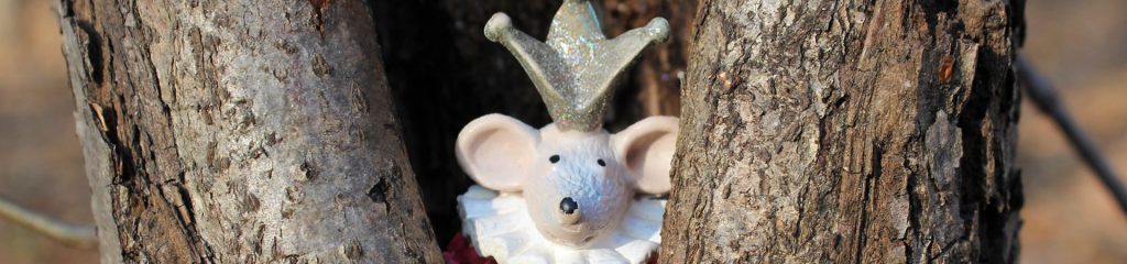 a toy mouse with a crown on in a tree