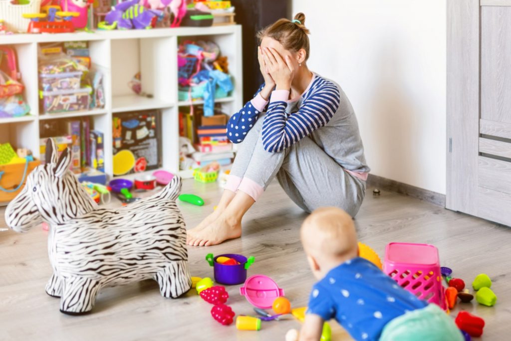 A mother sitting on the floor in her toddlers nursery upset and struggling to cope