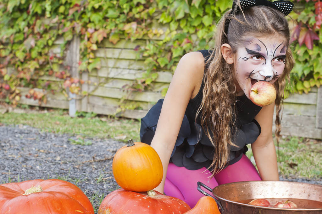 a girl bobbing or dooking for apples at halloween