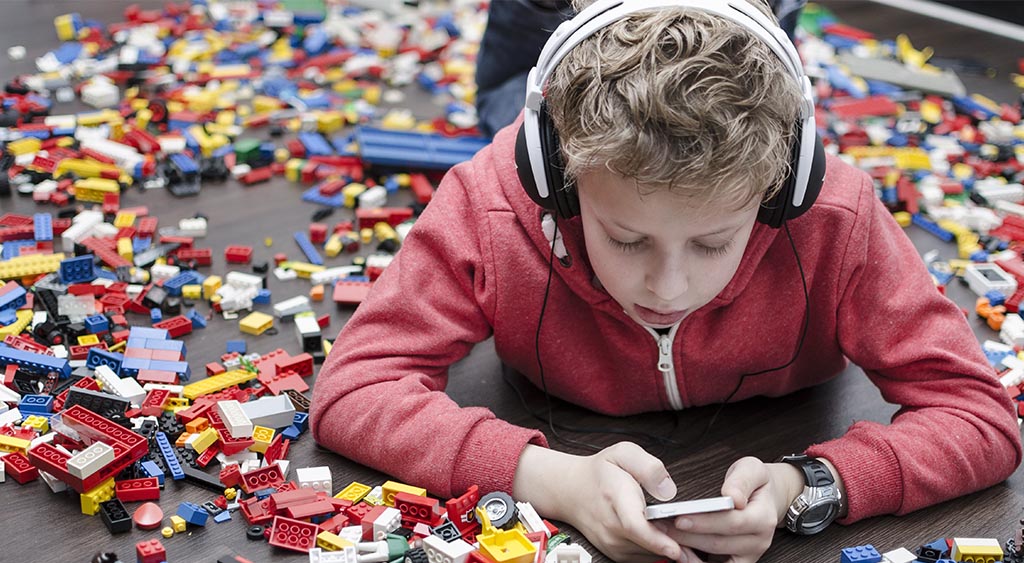 a kid surrounded by lego on his phone