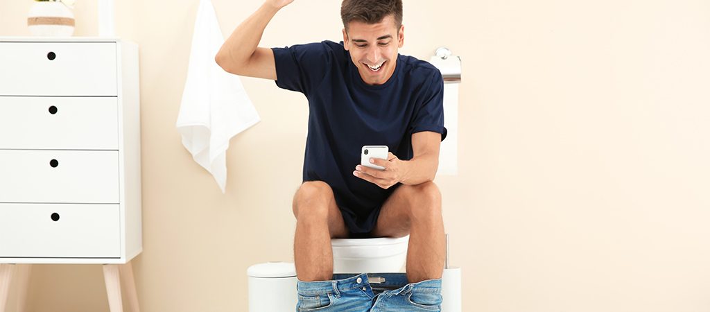 A man on the toilet has just won on his mobile phone game