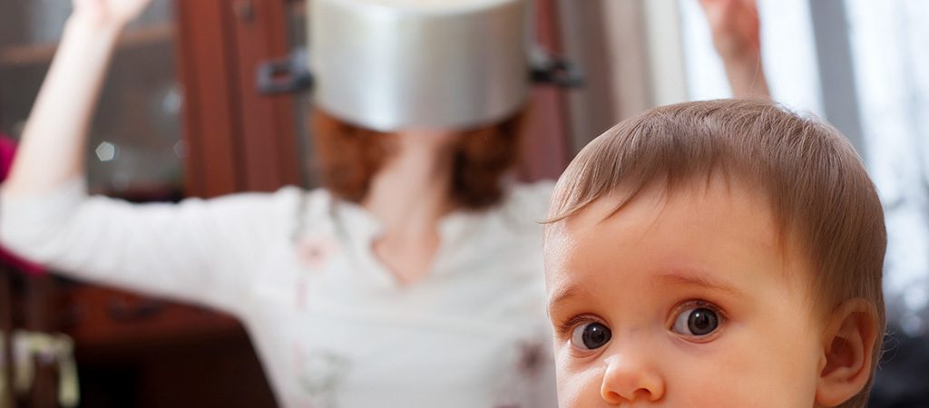 a baby looks confused as his mum has a pot on her head